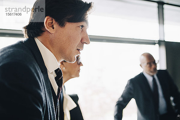 Geschäftsmann schaut weg  während er mit Kollegen bei einer Besprechung im Büro steht
