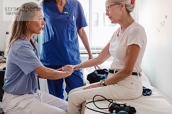 Arzt kontrolliert den Puls einer älteren Frau im medizinischen Untersuchungsraum