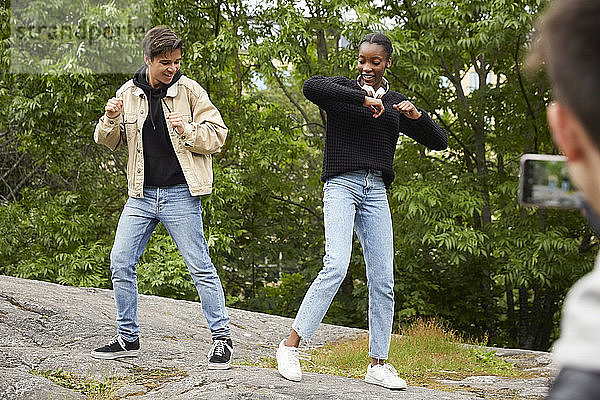 Ausschnitt eines Teenagers  der Freunde fotografiert  die im Park auf einem Felsen tanzen