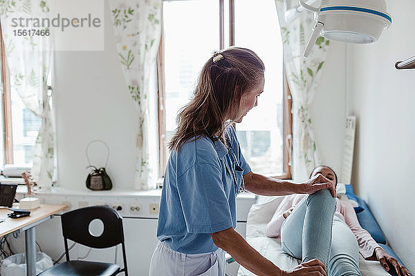 Krankenschwester untersucht das Bein des Patienten in der Klinik