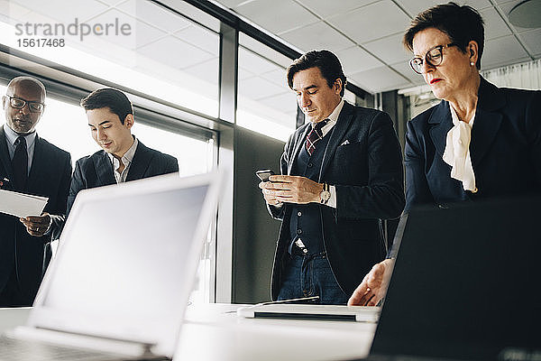 Geschäftsleute arbeiten  während sie im Sitzungssaal im Büro stehen