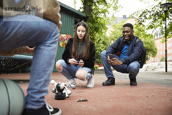 Freunde steuern Roboter mit Smartphone während einer Schlacht im Park