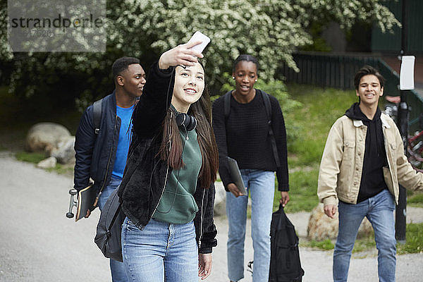 Lächelndes Teenagermädchen  das sich beim Gehen auf der Straße gegen Freunde stellt