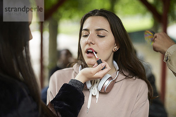 Teenager-Mädchen trägt Lippenstift auf Freundin im Park auf