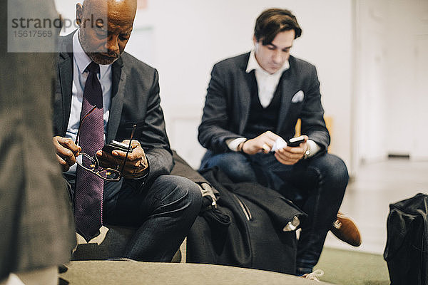 Geschäftsleute benutzen Mobiltelefone  während sie im Büro sitzen