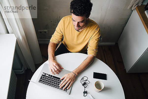 Hochwinkelansicht eines mittleren erwachsenen Mannes mit Laptop am Tisch