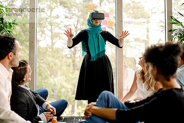 Geschäftsfrau trägt einen Virtual-Reality-Simulator während einer Konferenz mit Kollegen im Kongresszentrum