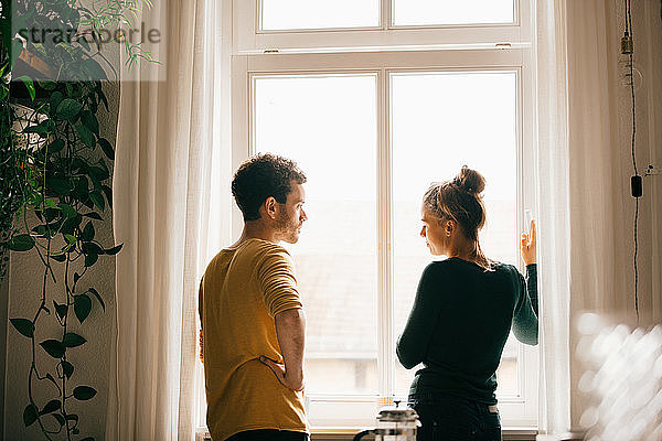 Paar redet  während es zu Hause am Fenster steht