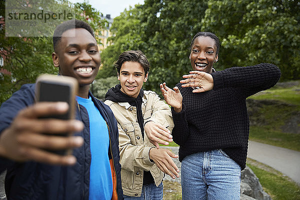 Glückliche Freunde schauen auf Smartphone  während sie im Park Tanz üben