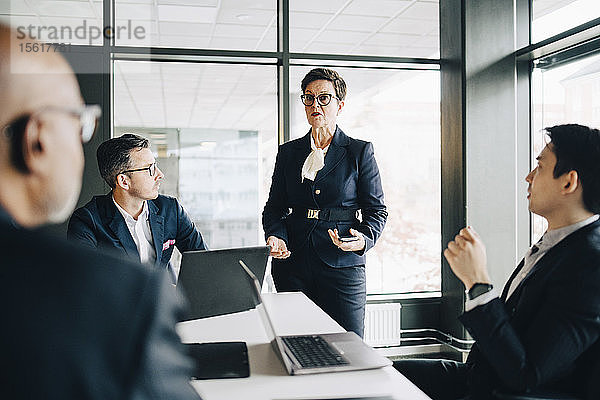 Leitende Geschäftsfrau erklärt Mitarbeitern im Konferenzraum während einer Besprechung im Büro