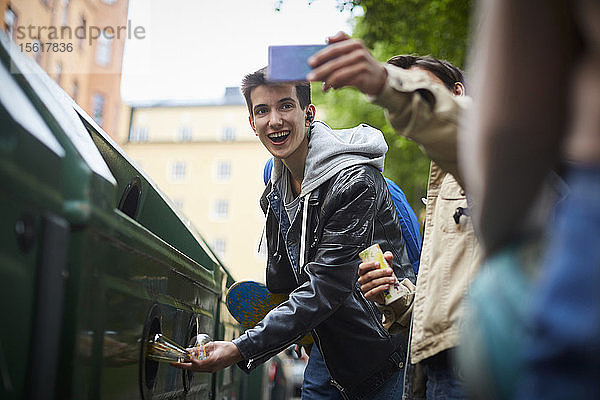 Mann nimmt Selfie mit Teenager-Freund mit und wirft Abfall in den Mülleimer an der Recycling-Station