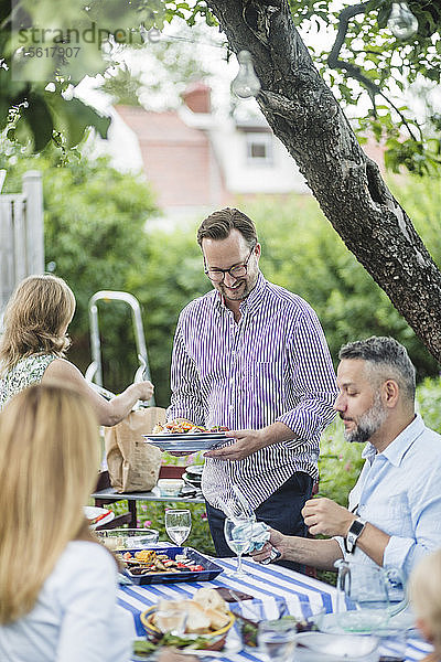 Ältere Freunde genießen und teilen das Essen am Tisch bei der Wochenendparty