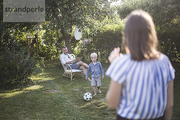 Vater sieht Sohn beim Fussballspielen mit Tochter im Garten