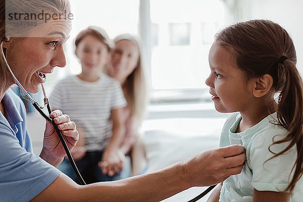 Weibliche Kinderärztin hört den Herzschlag des Mädchens durch ein Stethoskop in der Klinik ab