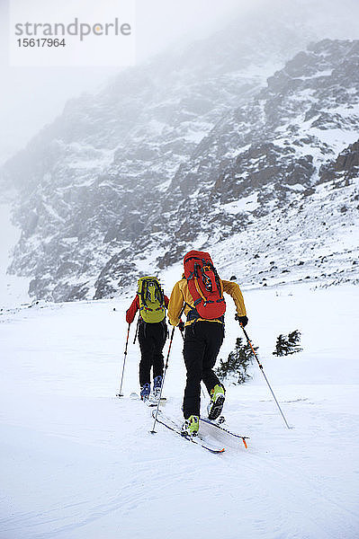 Bergsteiger nähern sich der Nordwand des Ptarmigan Peak (4.910 Fuß) auf Skiern während eines stürmischen Tages im Chugach State Park  in der Nähe von Anchorage  Alaska  Februar 2011. (Modellfreigabe: Agnes Hage  Kyle Irwin)