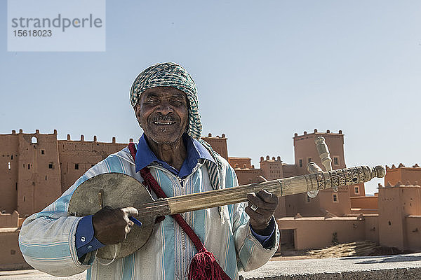 Aufnahme eines einheimischen Berbermannes  der ein Saiteninstrument für Touristen in Marokko spielt