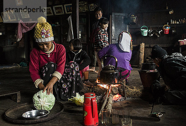 Drei-Generationen-Familie sitzt am Lagerfeuer in einem kleinen ländlichen Haus  Myanmar  Shan  Myanmar