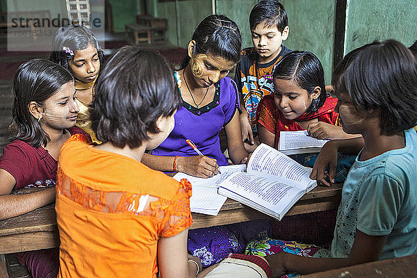 Der Klassenlehrer vergleicht Notizen für die Schüler der Hindi-Klasse im Arya Gurukul  Arya Samaj Temple  Zyd  das am 20.02.2012 eröffnet wurde. Jiwabari  Myanmar.