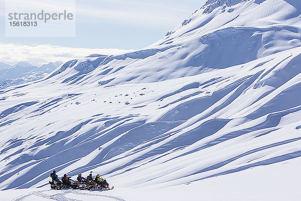 Gruppe von Snowboardern mit Motorschlitten im Norden von British Columbia