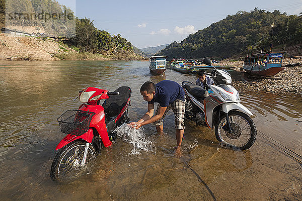 Männer spülen ihre Motorroller im Fluss Nam Ou in Muang Khua  Laos  ab.