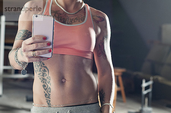 Sportliche Frau macht ein Selfie mit Smartphone nach dem Training im Fitnessstudio