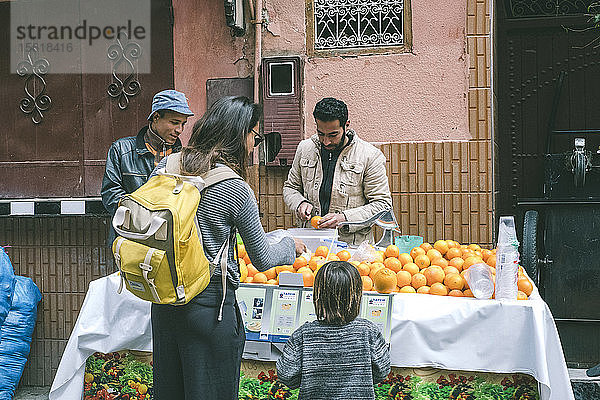 Mutter mit Sohn kauft frischen Orangensaft auf dem Straßenmarkt in der Medina  Marrakesch  Marokko