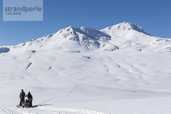 Snowboarder mit ihrem Schneemobil beim Wandern im Norden von British Columbia