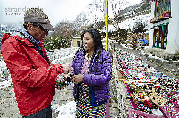 Mann im Gespräch mit einer Frau  die im Winter auf der Straße Schmuck verkauft  Solukhumbu  Nepal