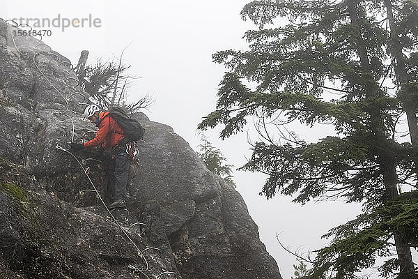 Ein Mann schiebt beim Klettern auf dem Klettersteig in Squamish  British Columbia  seine Schlinge zum nächsten Seil hinauf.
