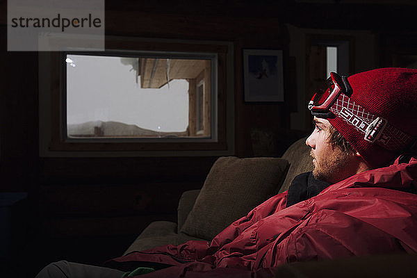 Junger Mann ruht sich nach dem Snowboarding in Mica Creek Heli  British Columbia  Kanada  in der Hütte aus