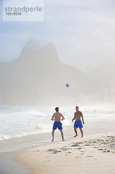 Zwei Männer beim Fußballspielen in der Brandung am Strand von Ipanema  Rio De Janeiro  Brasilien