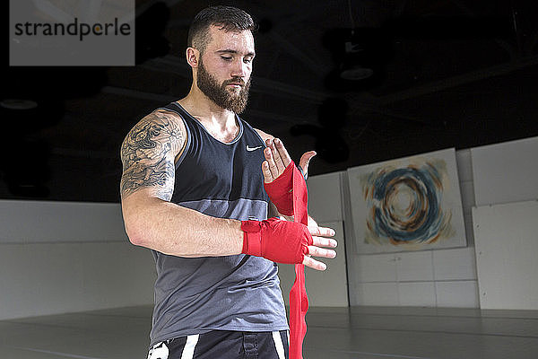 Der aufstrebende Mixed Martial Arts-Kämpfer Sean Lally wickelt seine Hände vor dem Training im Fitnessstudio.