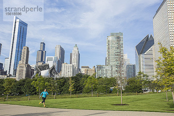 Eine erwachsene Frau läuft durch den Millenium Park mit der Skyline der Innenstadt von Chicago im Hintergrund. Chicago  Illinois.