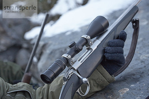 Hände einer Person  die ein Gewehr mit Zielfernrohr im Freien hält  Neuseeland