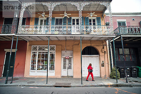 Eine Frau in roter Kleidung geht eine leere Straße in New Orleans  Louisiana  entlang.