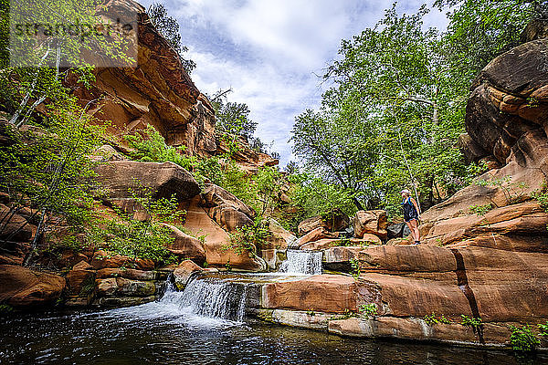 Fernsichtaufnahme einer Wanderin in der Nähe eines Wasserfalls am West Clear Creek  Arizona  USA