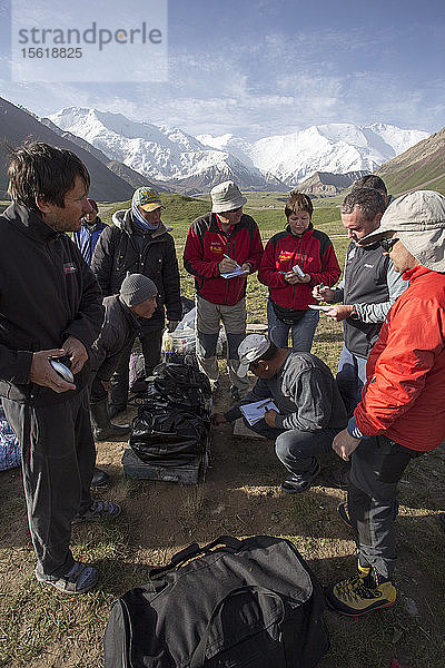 Eine Gruppe von Bergsteigern verhandelt im Basislager des Lenin-Gipfels (Kirgisistan) über den Preis für die Träger.