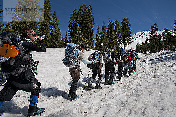 Jungen im Alter von 13 bis 17 Jahren von der Venturing Crew 191 aus Glendora  Kalifornien  setzen ein Jahr Training in die Praxis um  als sie versuchen  den Gipfel des Mount Shasta über die Avalanche Gulch-Route im Shasta Trinity National Forest in Nordkalifornien zu erreichen. Der Mount Shasta ist ein massiver  vergletscherter Vulkan und mit 14.179 Fuß der zweithöchste Gipfel in der Cascade Range und der fünfthöchste in Kalifornien; er ist mit keinem anderen Gipfel verbunden und erhebt sich abrupt 10.000 Fuß über das umliegende Gelände. Die Pfadfinder der Venturing Crew 191 (Venturing Crews sind ein Zweig der Pfadfinder  der sich auf abenteuerliche Aktivitäten konzentriert) hatten sich ein Jahr lang auf die Besteigung des Mount Shasta vorbereitet. Es war ihre erste Erfahrung mit dem Klettern in steilem Schnee  und sie wurden bei der Besteigung von Führern der SWS Mountain Guides unterstützt. Jeremy Kolbach  Vorsitzender der Crew  Sandy Howlett  Crew-Mitglied Tristan Rodriquez (von links nach rechts) und andere Mitglieder der Venturing-Crew 191 wandern auf dem Weg zu einem Hochlager am Fuße des Mount Shasta durch den Schnee. Von dort aus werden sie versuchen  den Gipfel des Mount Shasta über die Avalanche Gulch-Route zu erreichen  Shasta Trinity National Forest  Nordkalifornien.