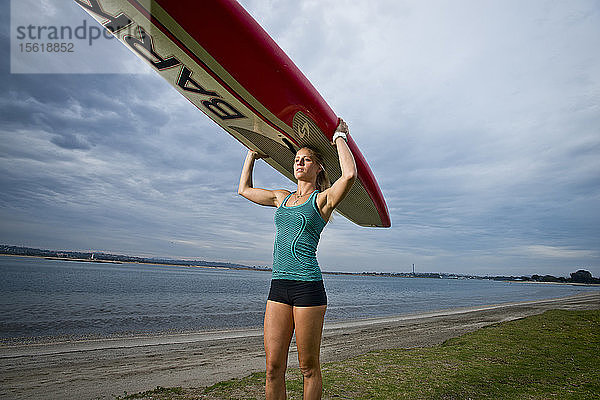 Ein Mädchen geht mit ihrem Paddelbrett auf dem Kopf in San Diego  Kalifornien  zum Wasser.