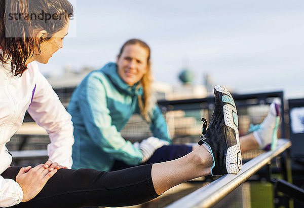 Zwei Läuferinnen in Sportkleidung dehnen ihre Kniesehnen nach dem Joggen in der Nähe des Puget Sound  Seattle  Bundesstaat Washington  USA