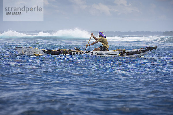 Foto eines einheimischen samoanischen Fischers  der in einem Auslegerkanu paddelt  Samoa