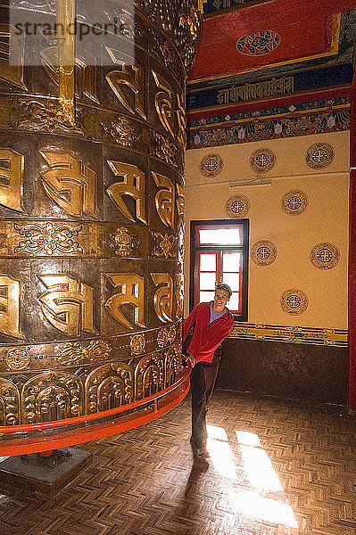 Glücklicher Mann beim Drehen einer riesigen Gebetsmühle im Kloster Tashiding  Sikkim  Indien