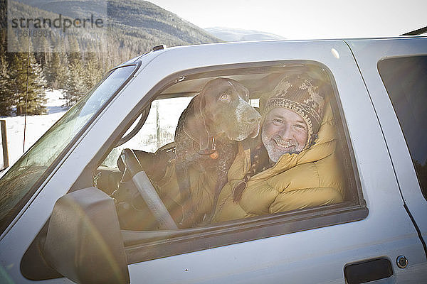 Porträt eines Mannes  der mit seinem Hund im Führerhaus seines Lastwagens sitzt.