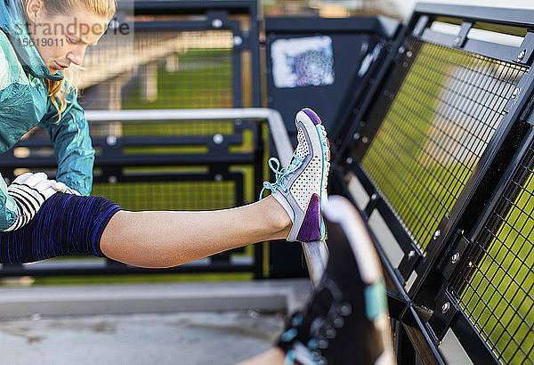 Läuferin in Sportkleidung dehnt Kniesehne nach dem Joggen in der Nähe des Puget Sound  Seattle  Bundesstaat Washington  USA