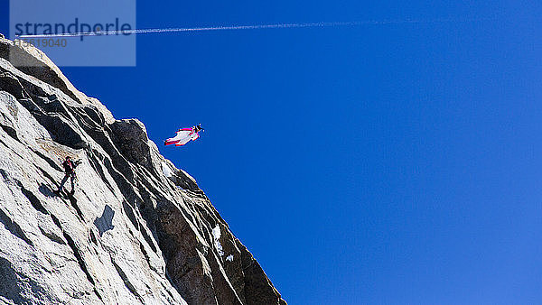 Eine Person springt von einer Klippe in einem Wingsuit in den Alpen