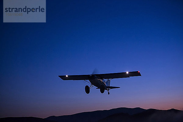 Silhouette eines Flugzeugs  das in der Abenddämmerung über die Wüste von Nevada fliegt