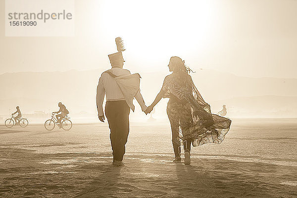 Ein Paar geht beim Burning Man in die untergehende Sonne.
