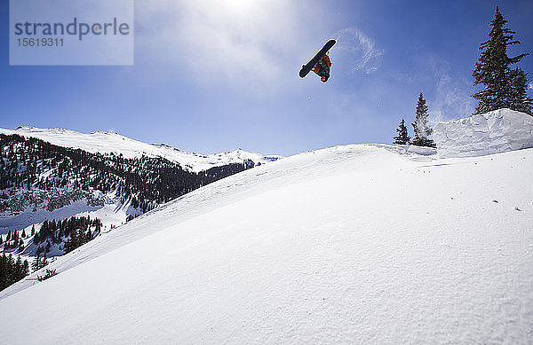 Ein Mann springt mit seinem Snowboard auf dem Red Mountain Pass im Südwesten Colorados ins Gelände.