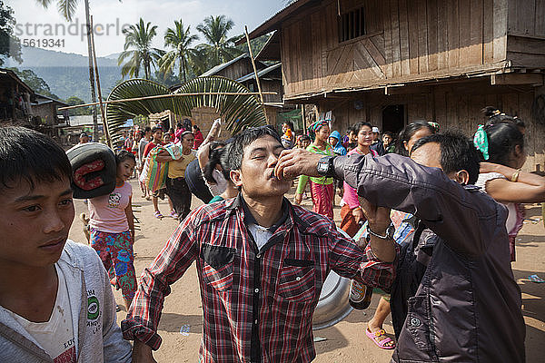 Einem Mann wird bei einer Hochzeitsprozession in Muang Hat Hin  Laos  ein Schuss Lao-lao (Reiswhisky) angeboten.