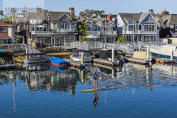 Entfernte Ansicht eines einzelnen Mannes beim Paddeln vor den Häusern am Wasser  Long Beach  Kalifornien  USA